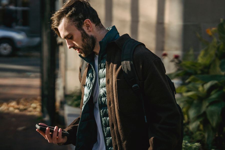 Personne consultant son téléphone dans une rue, en journée